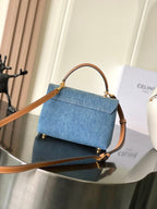 Denim top-handle flap bag with tan leather strap and gold-tone details, blue wash