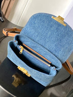 Denim flap bag open, showing zip pocket and tan leather trim, blue wash