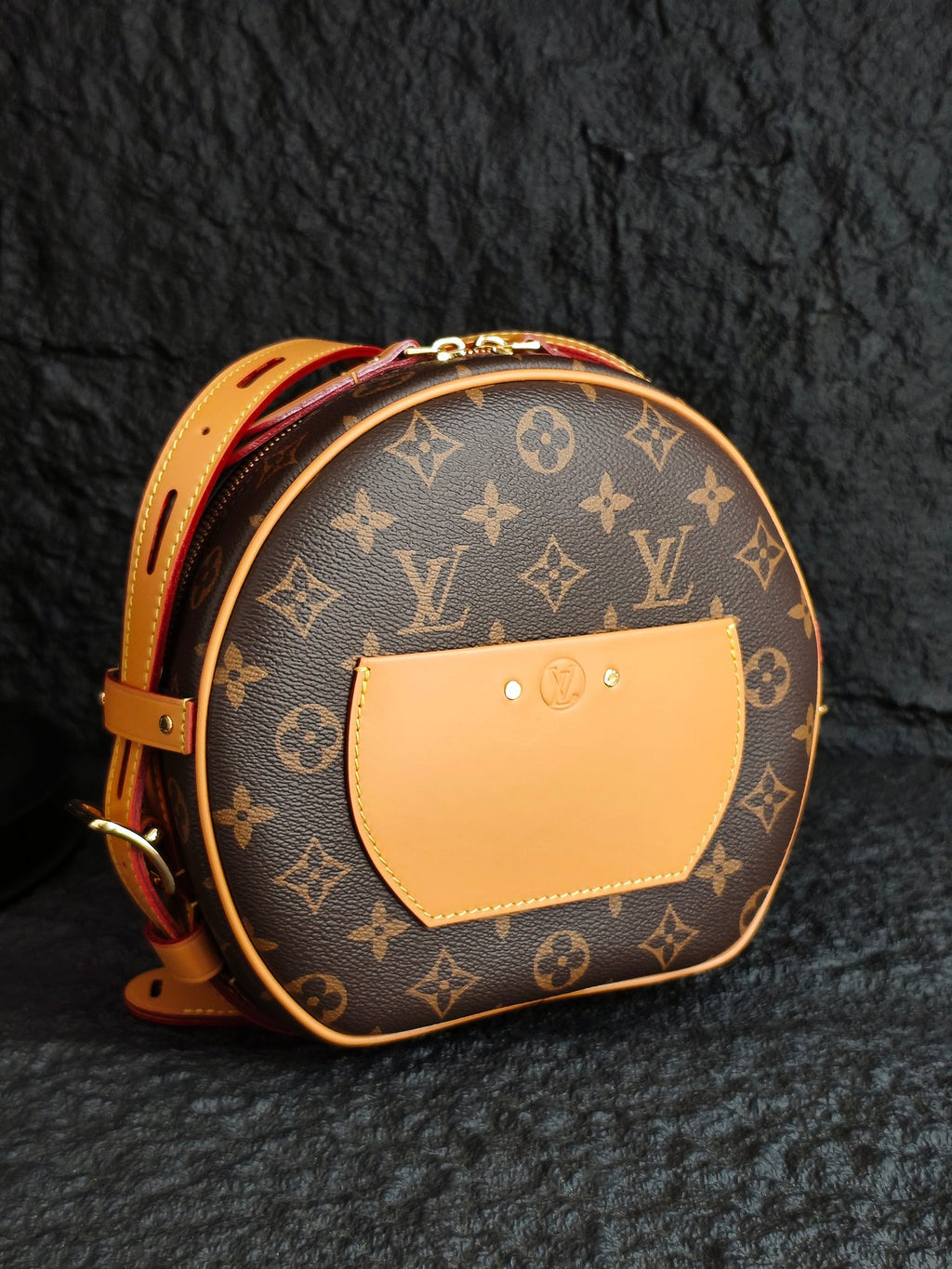 Round monogram canvas bag with tan front panel, tan strap, and gold hardware
