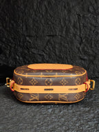 Monogram canvas bag with tan base strap, gold rings, and red zipper details
