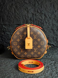 Round monogram canvas bag with tan leather trim and red-accent strap
