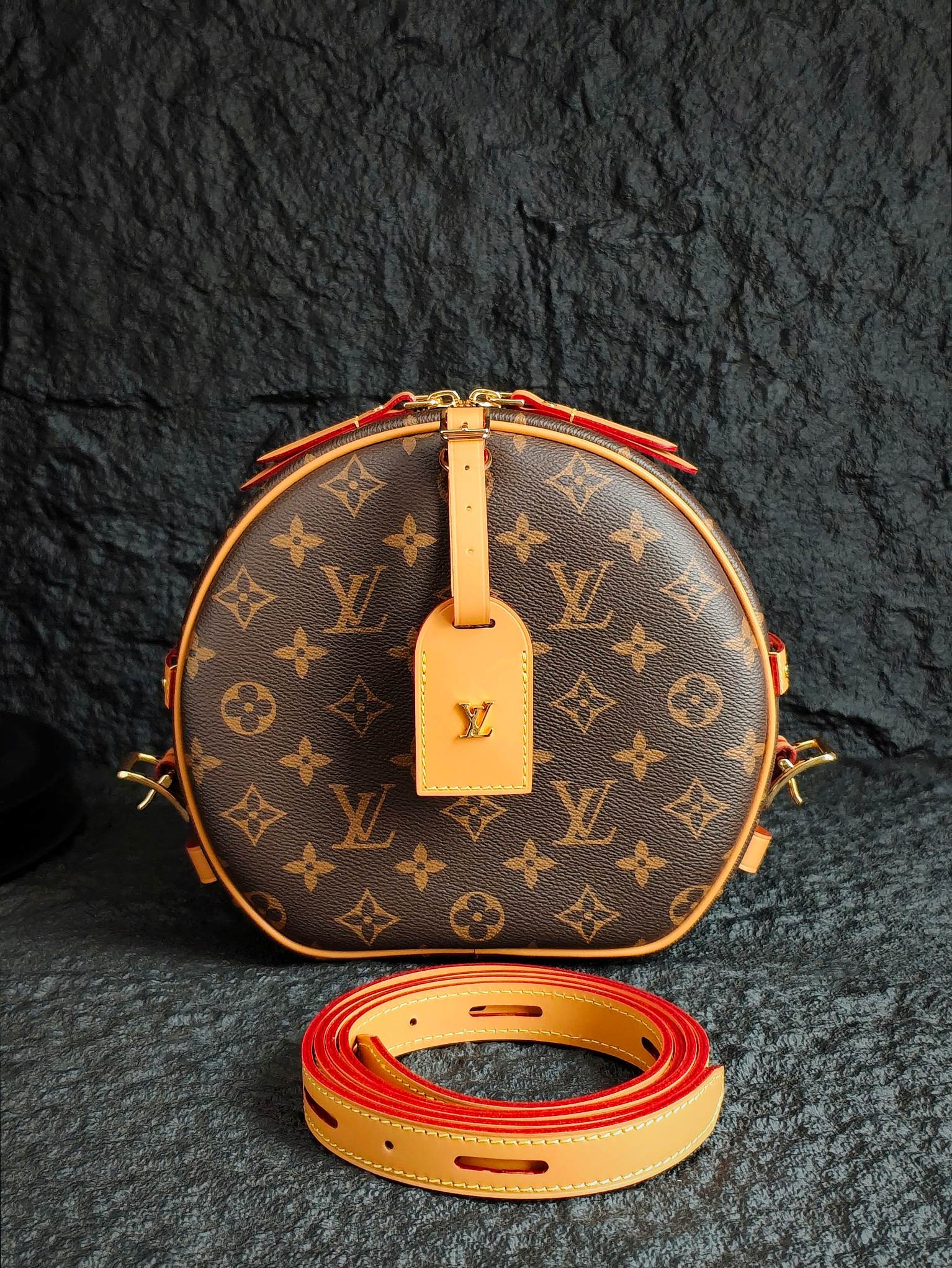 Round monogram canvas bag with tan leather trim and red-accent strap