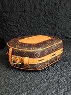 Monogram canvas bag with tan leather top, gold buckle, and tan shoulder strap