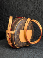 Monogram canvas backpack-style bag with tan straps and curved top silhouette