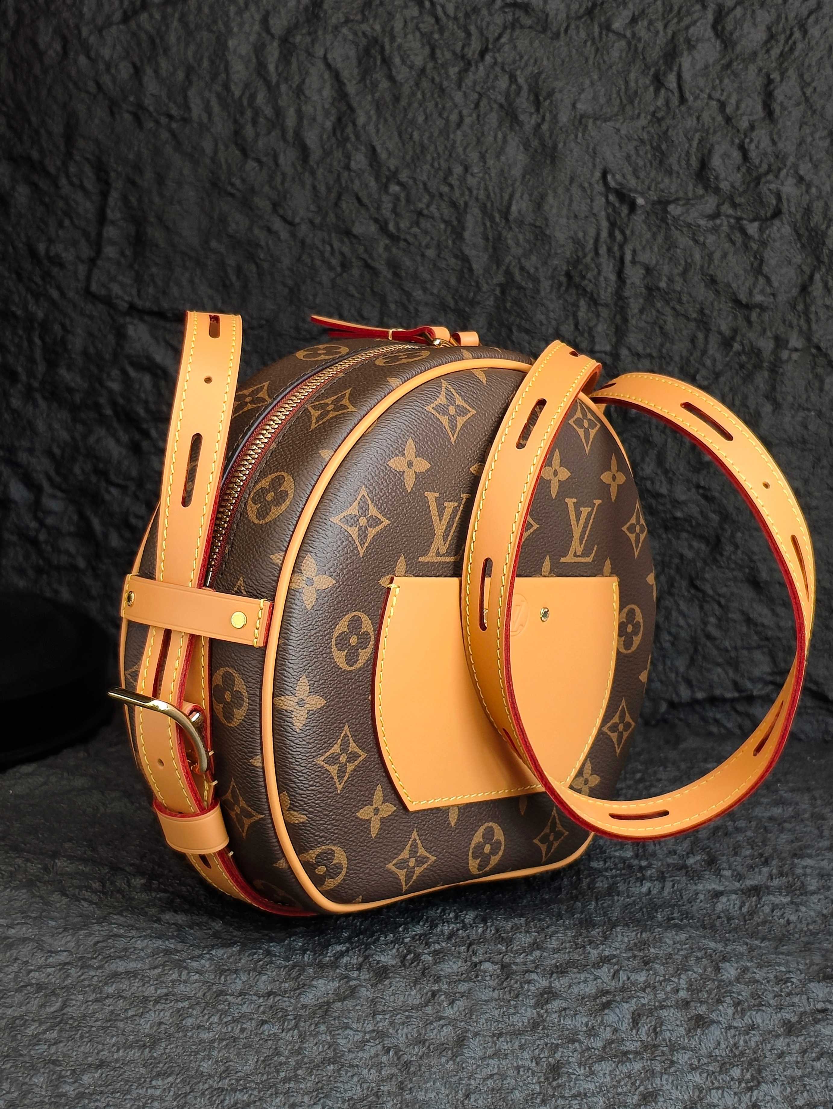 Monogram canvas backpack-style bag with tan straps and curved top silhouette