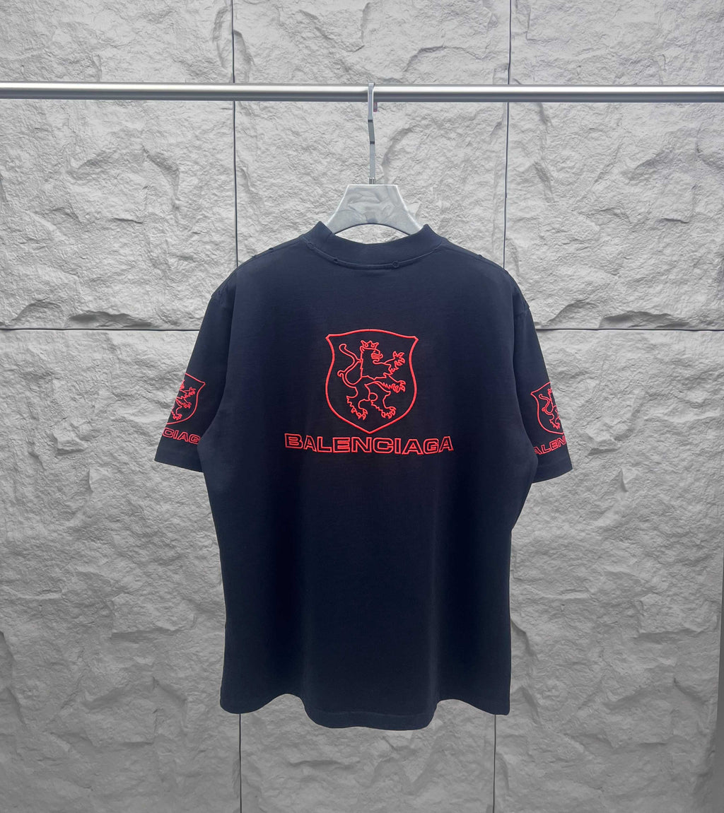 Balenciaga dark T-shirt with centered red shield crest and Balenciaga wordmark on front