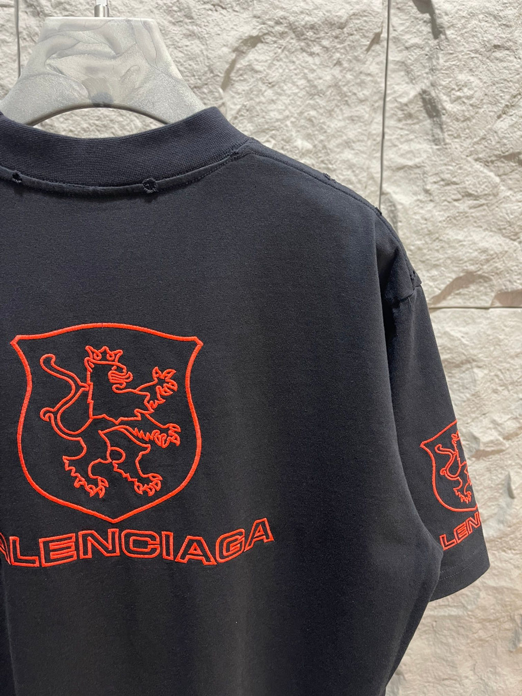 Balenciaga dark T-shirt back close-up with red shield crest and Balenciaga logo on sleeve