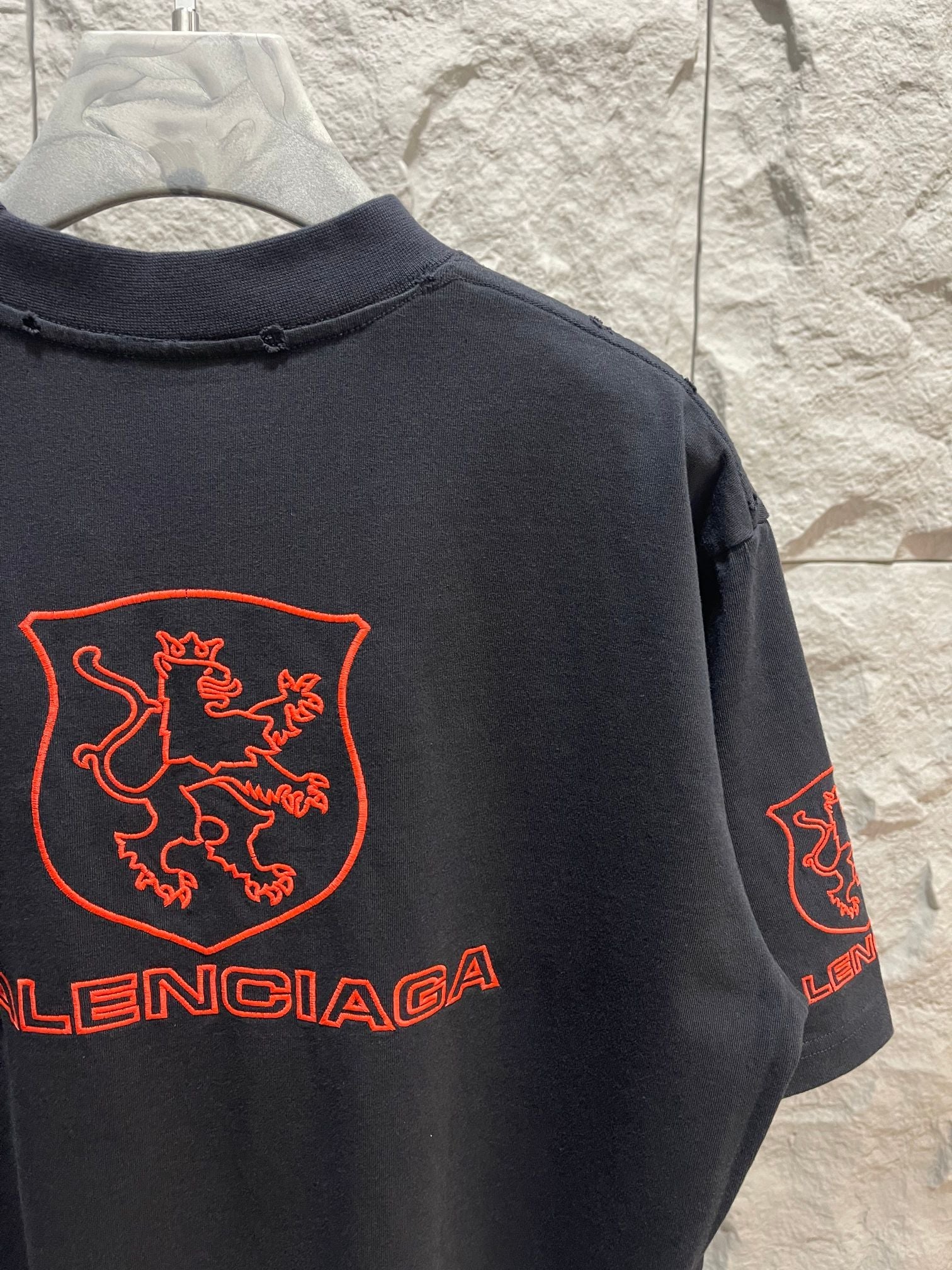 Balenciaga dark T-shirt back close-up with red shield crest and Balenciaga logo on sleeve