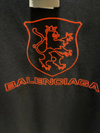 Balenciaga dark T-shirt extreme close-up of red shield crest and Balenciaga wordmark