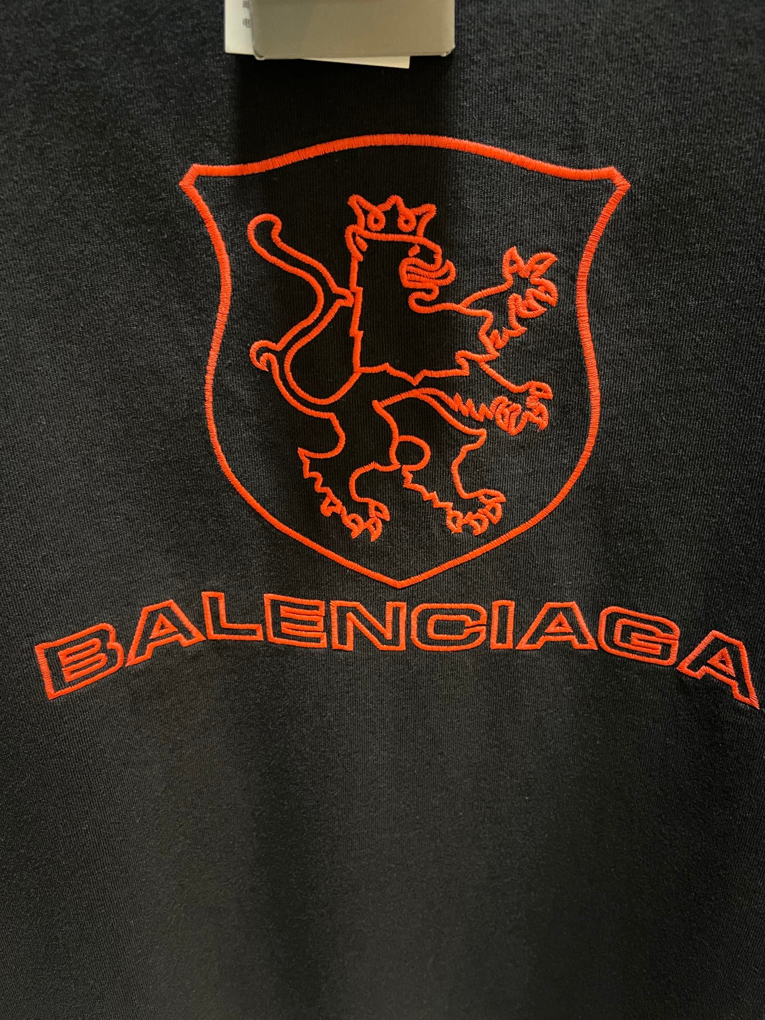 Balenciaga dark T-shirt extreme close-up of red shield crest and Balenciaga wordmark