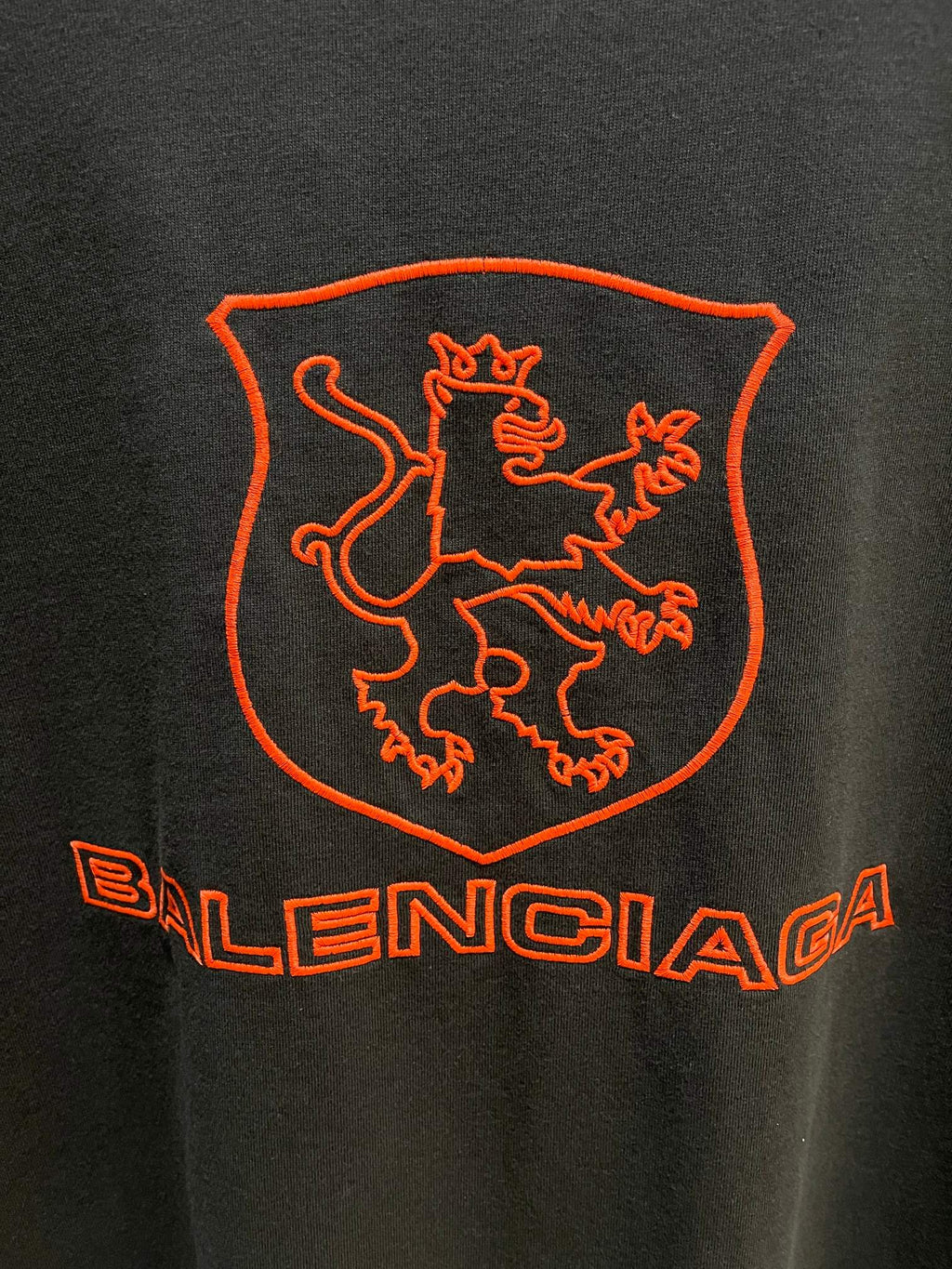 Balenciaga dark T-shirt back extreme close-up of red shield crest and Balenciaga wordmark