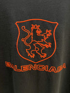 Balenciaga dark T-shirt back extreme close-up of red shield crest and Balenciaga wordmark