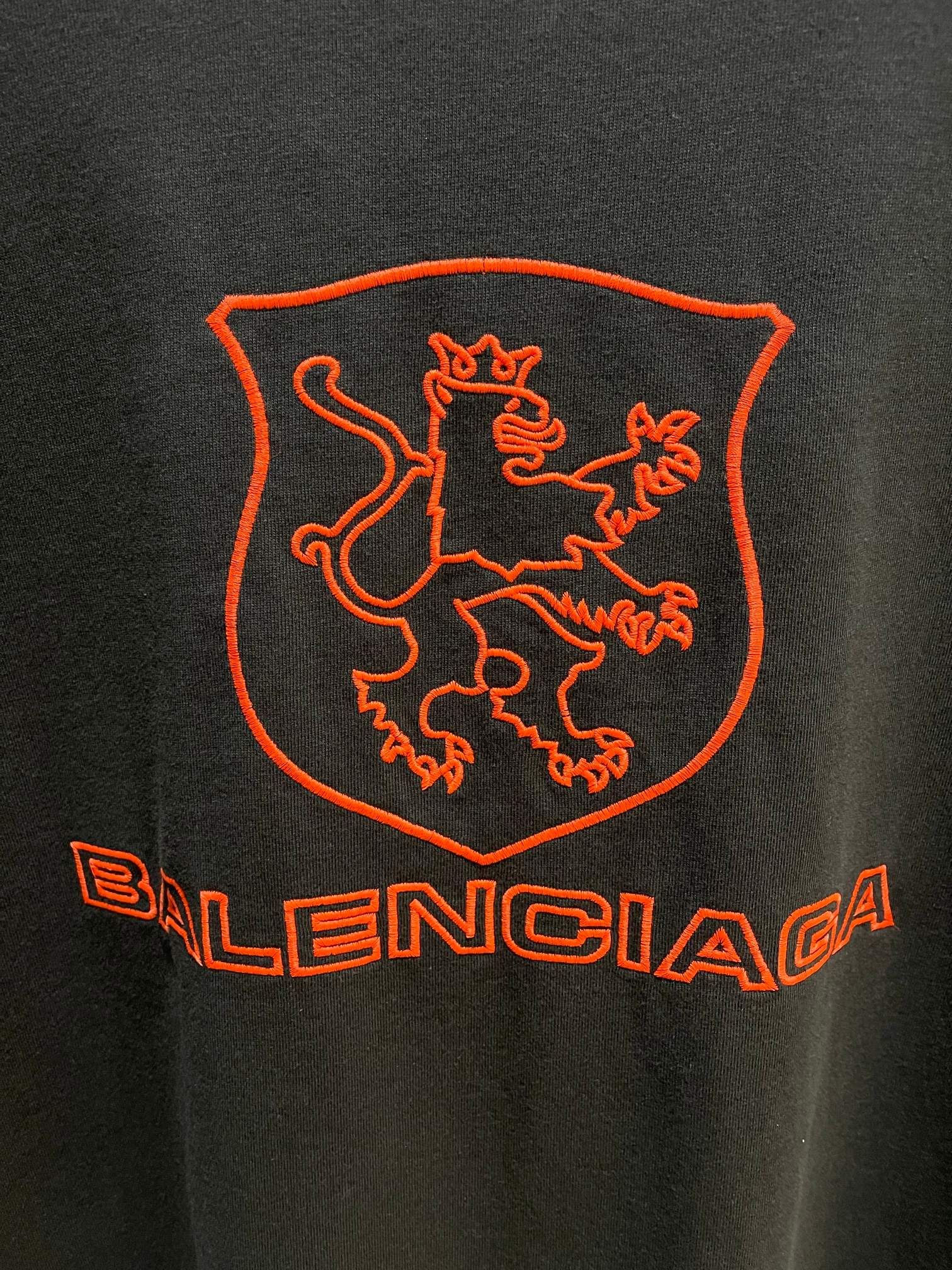 Balenciaga dark T-shirt back extreme close-up of red shield crest and Balenciaga wordmark