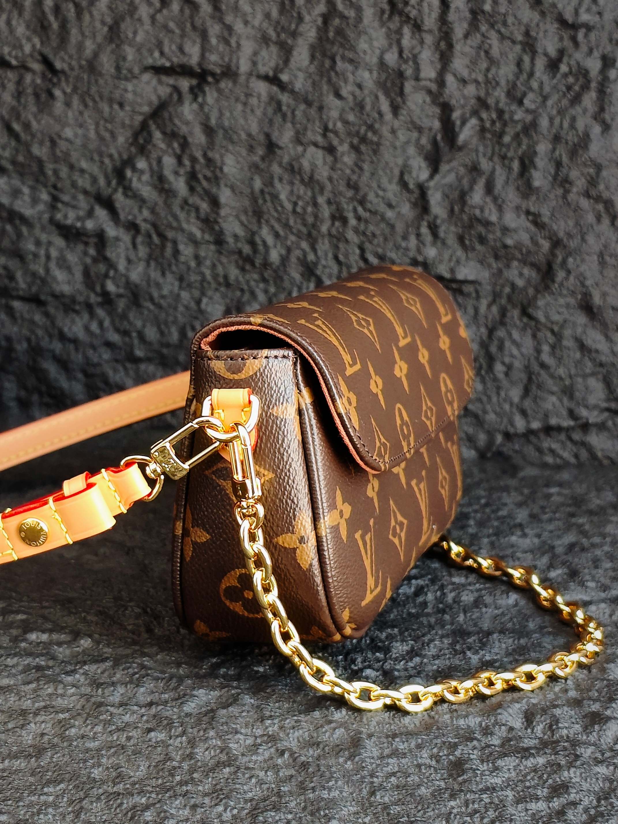 Louis Vuitton monogram mini bag with gold chain and tan strap, side view