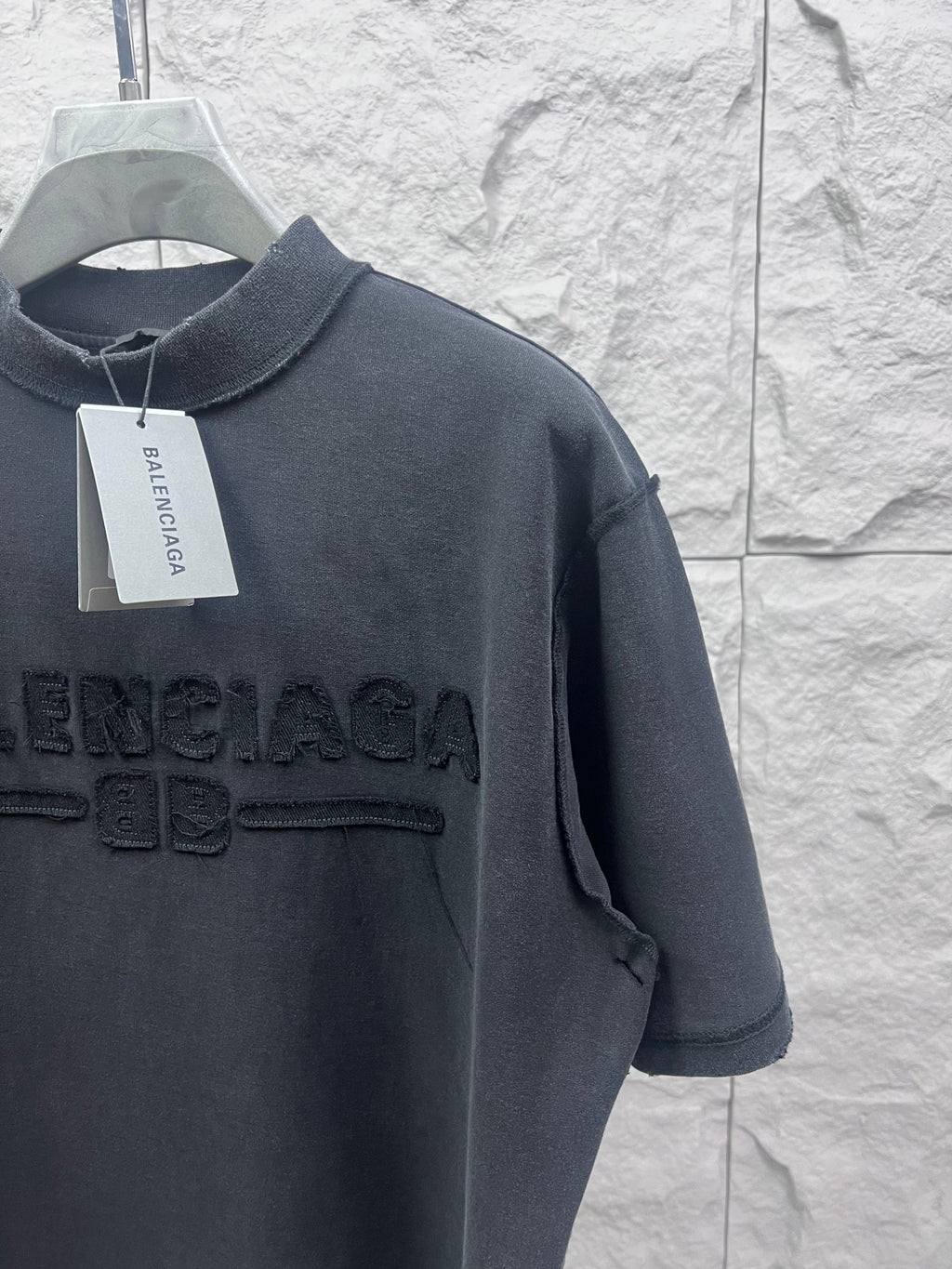 Dark T-shirt shoulder and chest close-up with embossed Balenciaga logo