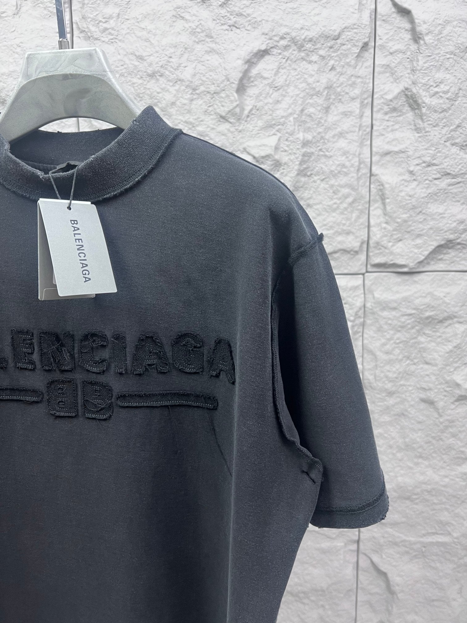 Dark T-shirt shoulder and chest close-up with embossed Balenciaga logo