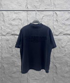 Dark crew-neck T-shirt with embossed Balenciaga logo on the chest