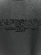 Dark T-shirt chest close-up showing embossed Balenciaga lettering and graphic