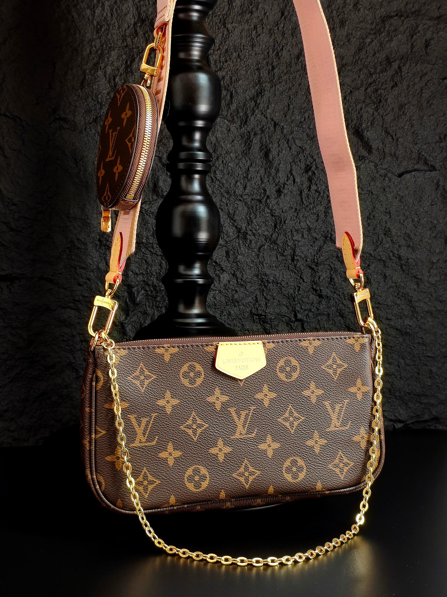 Louis Vuitton crossbody bag with monogram canvas, gold chain, and pink shoulder strap