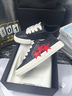Black sneakers with white laces and red star patch, white midsole