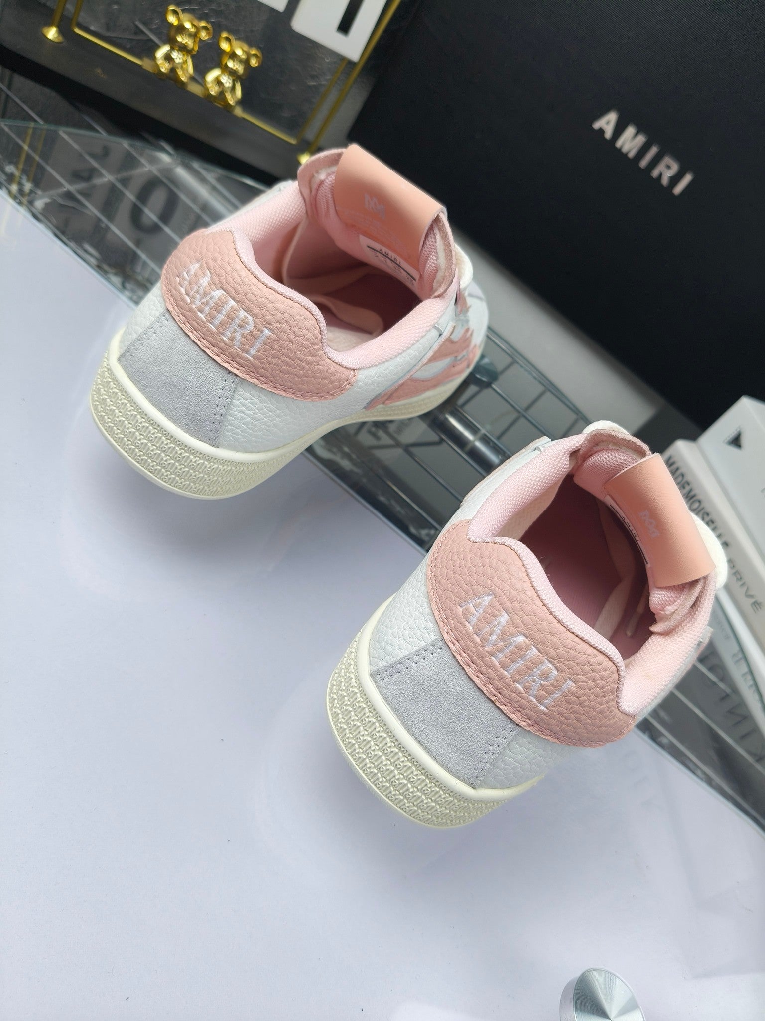 Amiri sneakers showing pink padded heel and white upper with lace-up front.