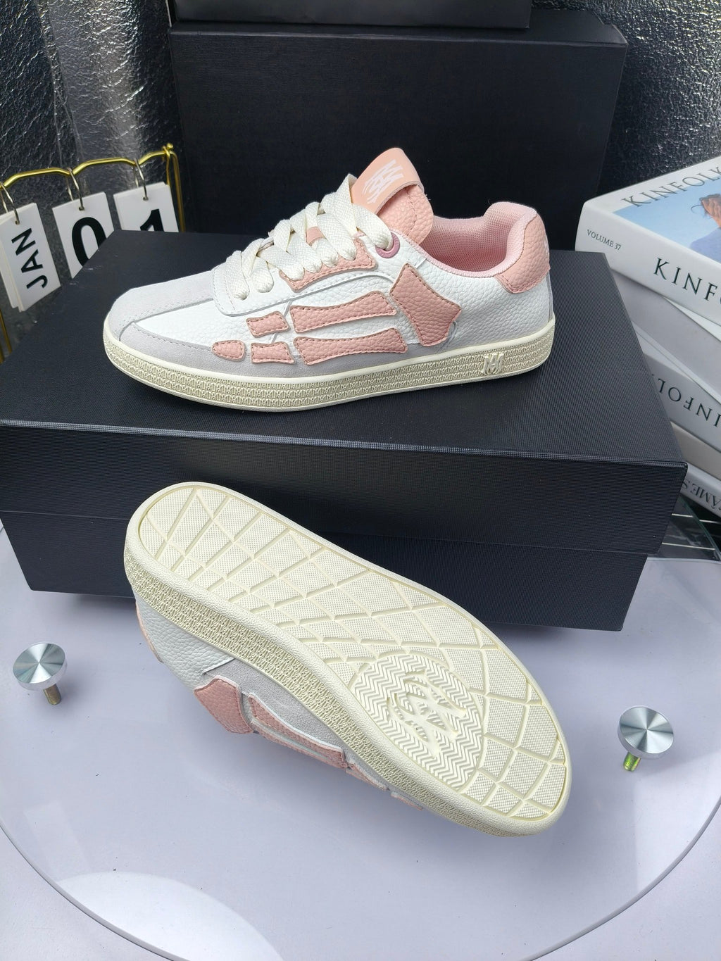 Amiri low-top sneakers in white with pink accents; outsole visible beneath.