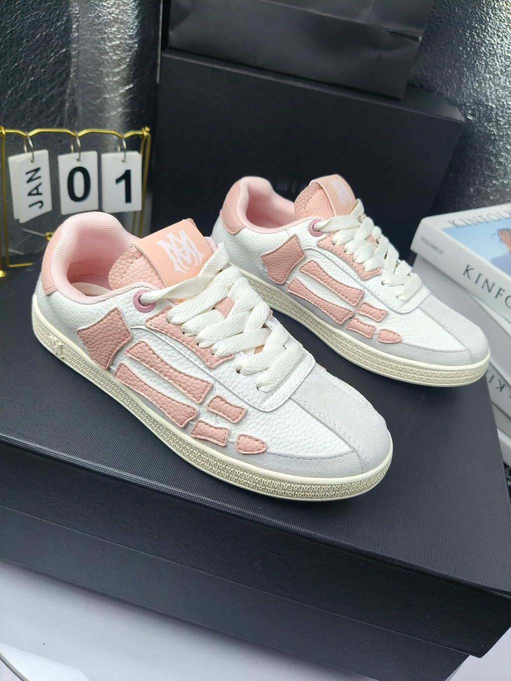 Amiri low-top sneakers in white with pink panels and lace-up design on display.