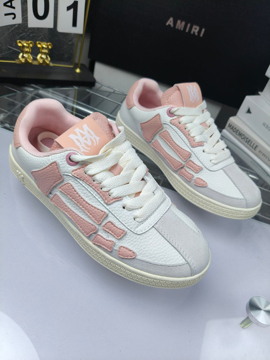 Amiri low-top sneakers, white with pink details and lace-up closure, side view pair.