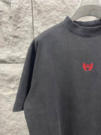 Balenciaga short-sleeve T-shirt close-up, dark gray, red chest logo.