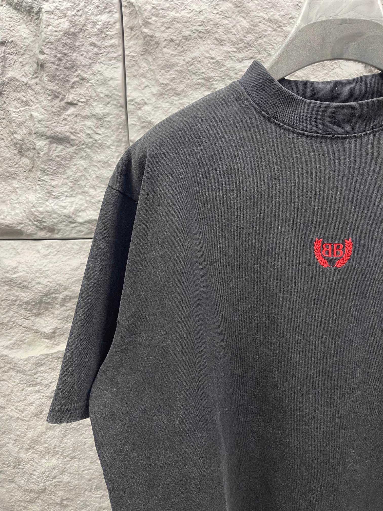Balenciaga short-sleeve T-shirt close-up, dark gray, red chest logo.