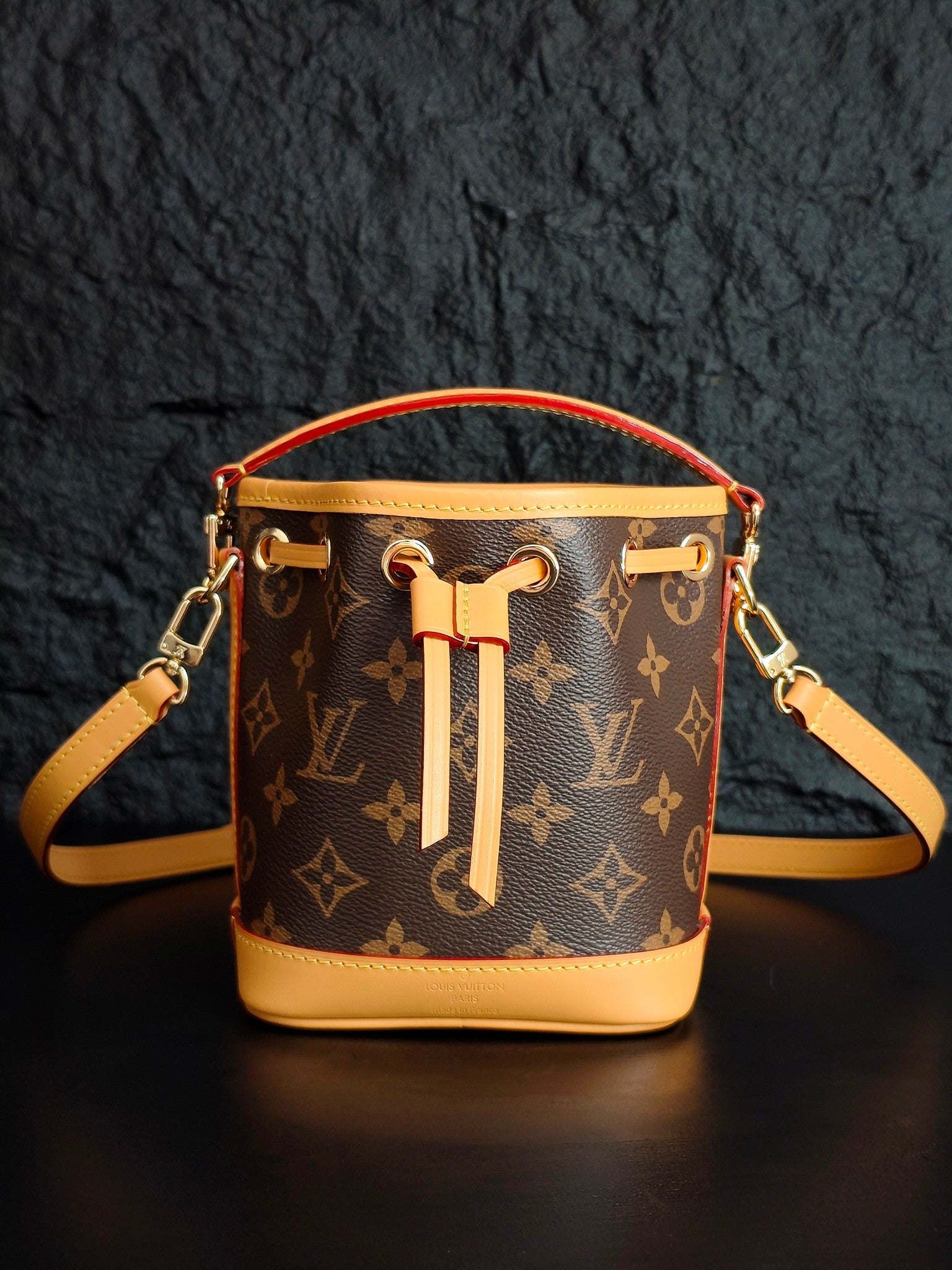 Louis Vuitton monogram bucket bag with crossbody strap and gold-tone rings