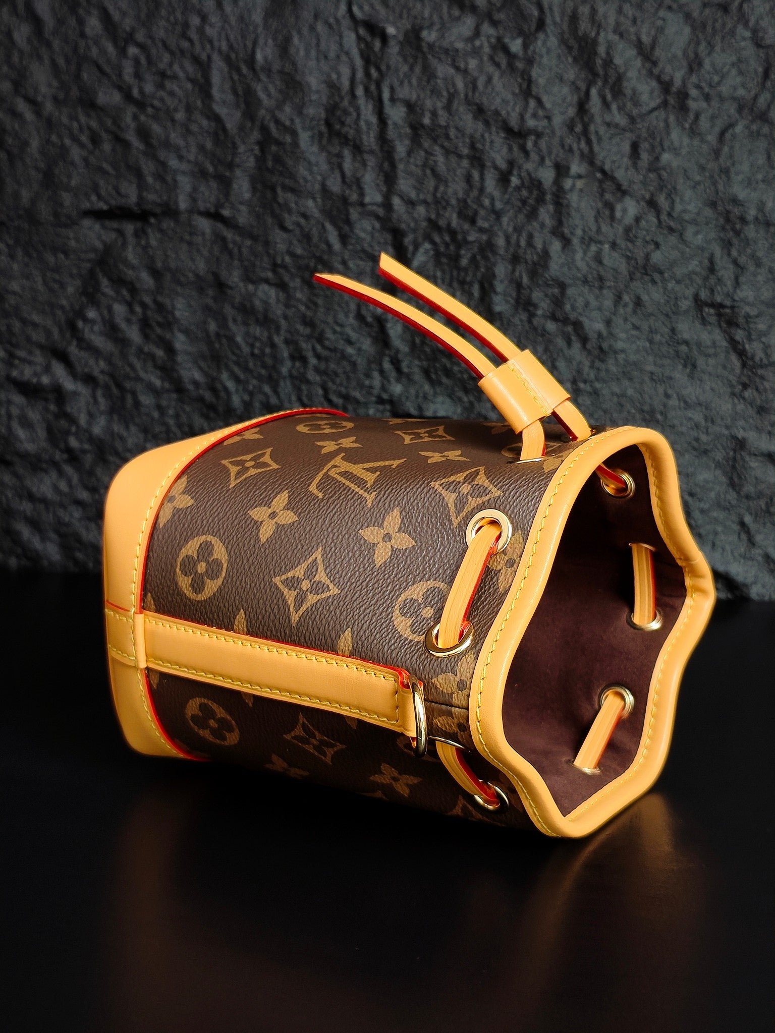 Louis Vuitton monogram bucket bag side view with top handle and red trim accents