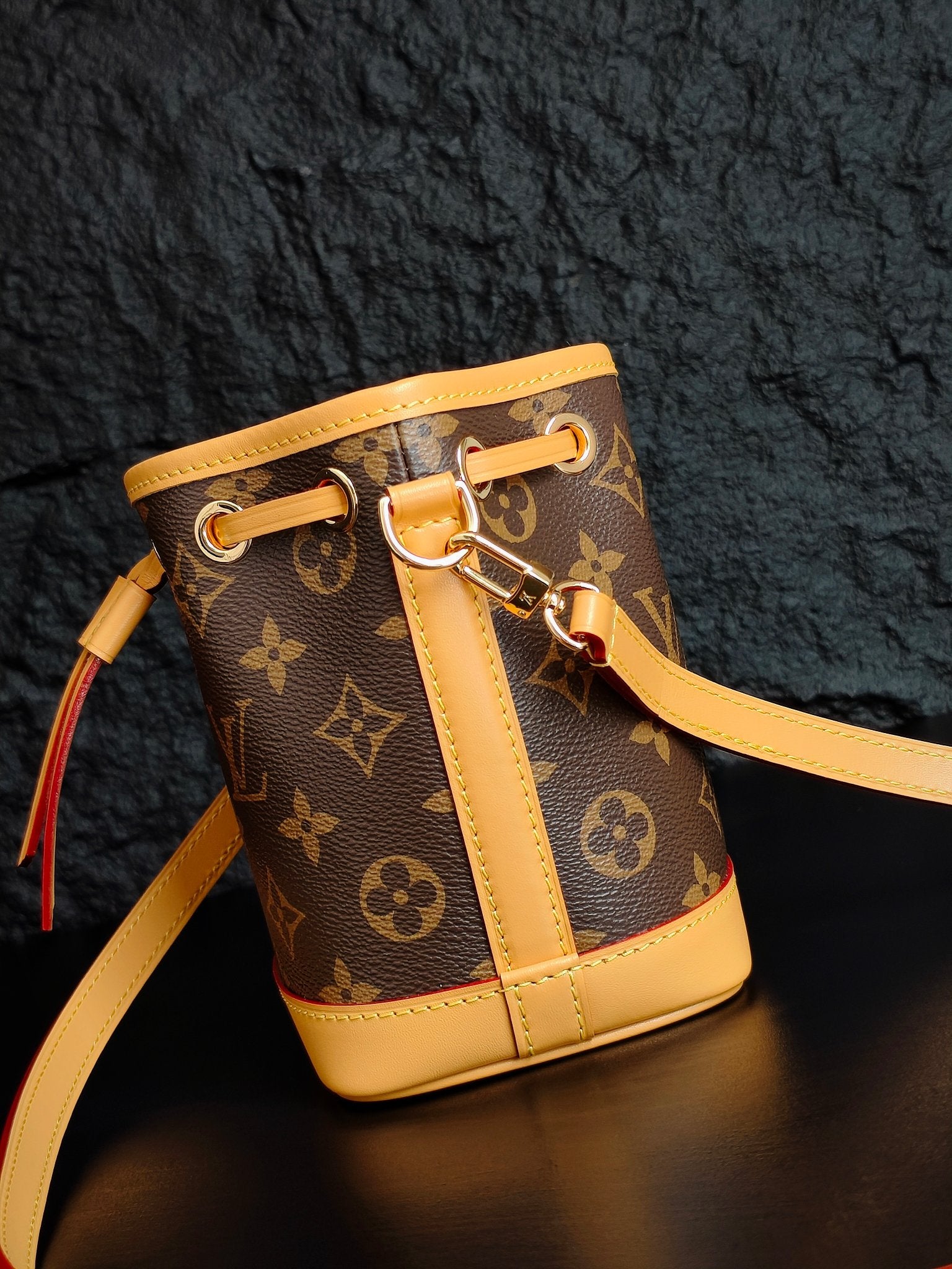 Louis Vuitton monogram bucket bag close-up of strap, buckle, and gold-tone hardware