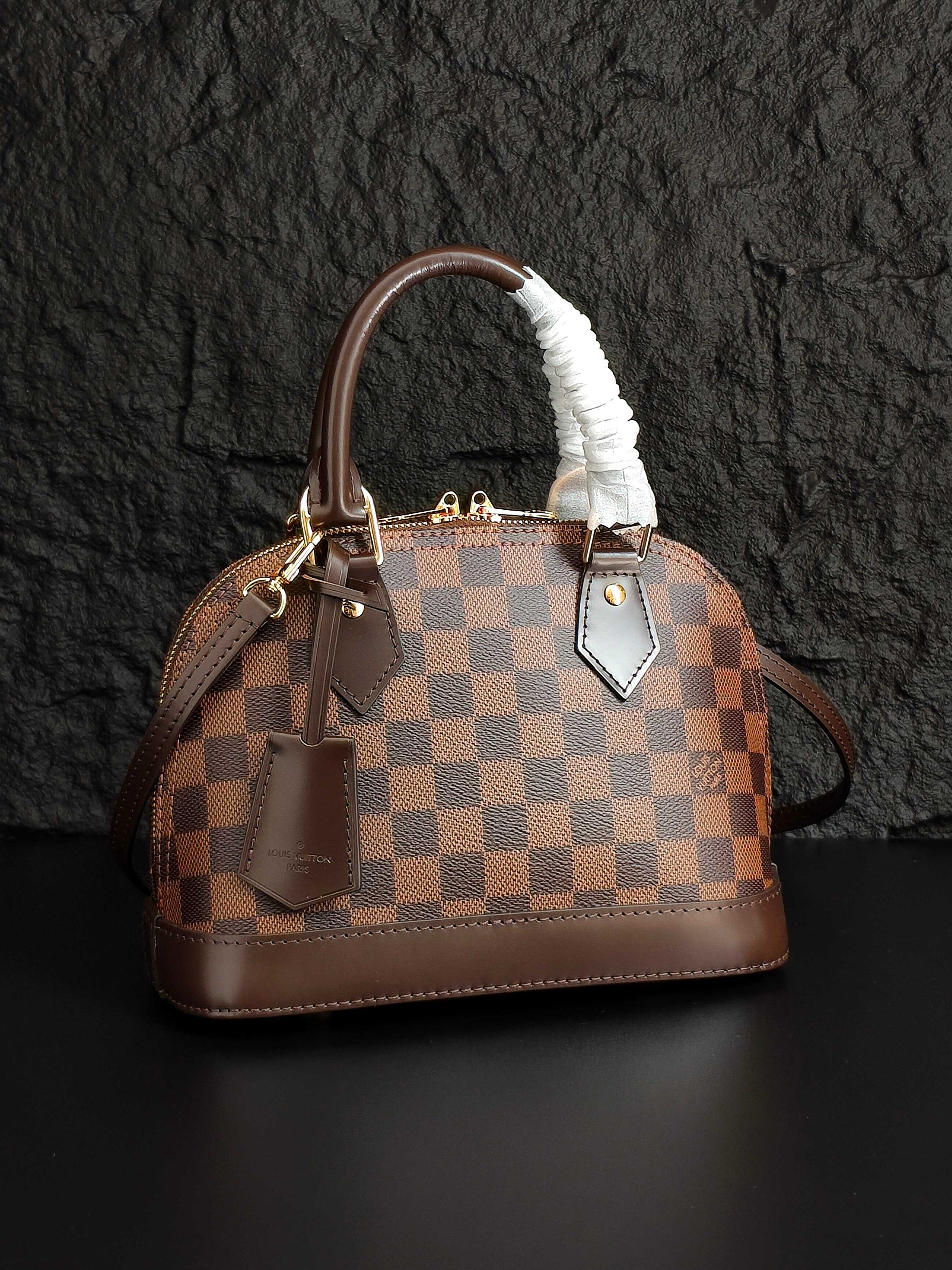 Louis Vuitton handbag with brown checkered canvas, fur-trimmed handle, front pocket details