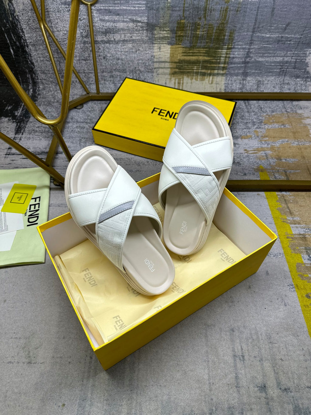 Fendi white slide sandals on yellow box, top view of the pair