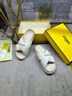 Fendi white slide sandals on a box, angled view, cross straps