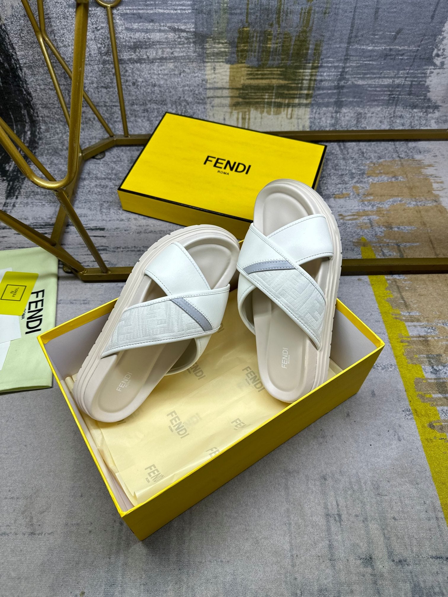 Fendi white slide sandals on yellow box with FENDI branding visible