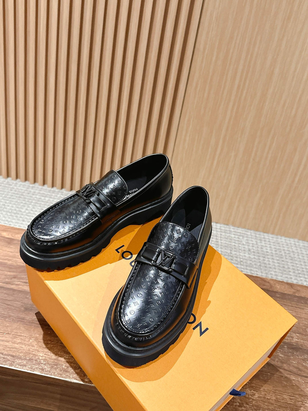 Black leather loafers with embossed monogram, buckle strap, and thick platform sole