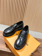 Black leather loafers with embossed monogram, buckle strap, and thick platform sole