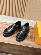 Pair of black leather loafers with monogram embossing and buckle strap