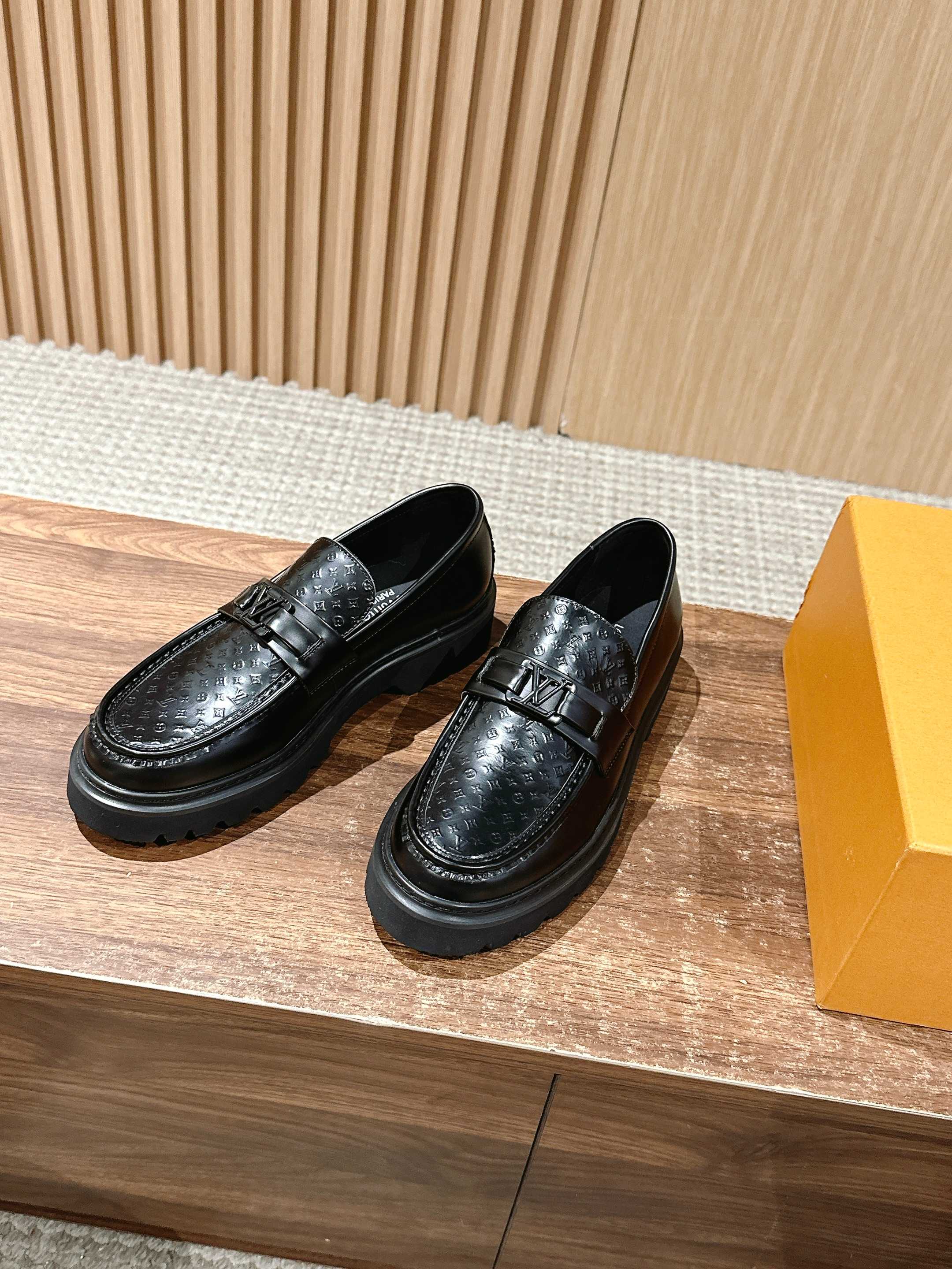 Pair of black leather loafers with monogram embossing and buckle strap