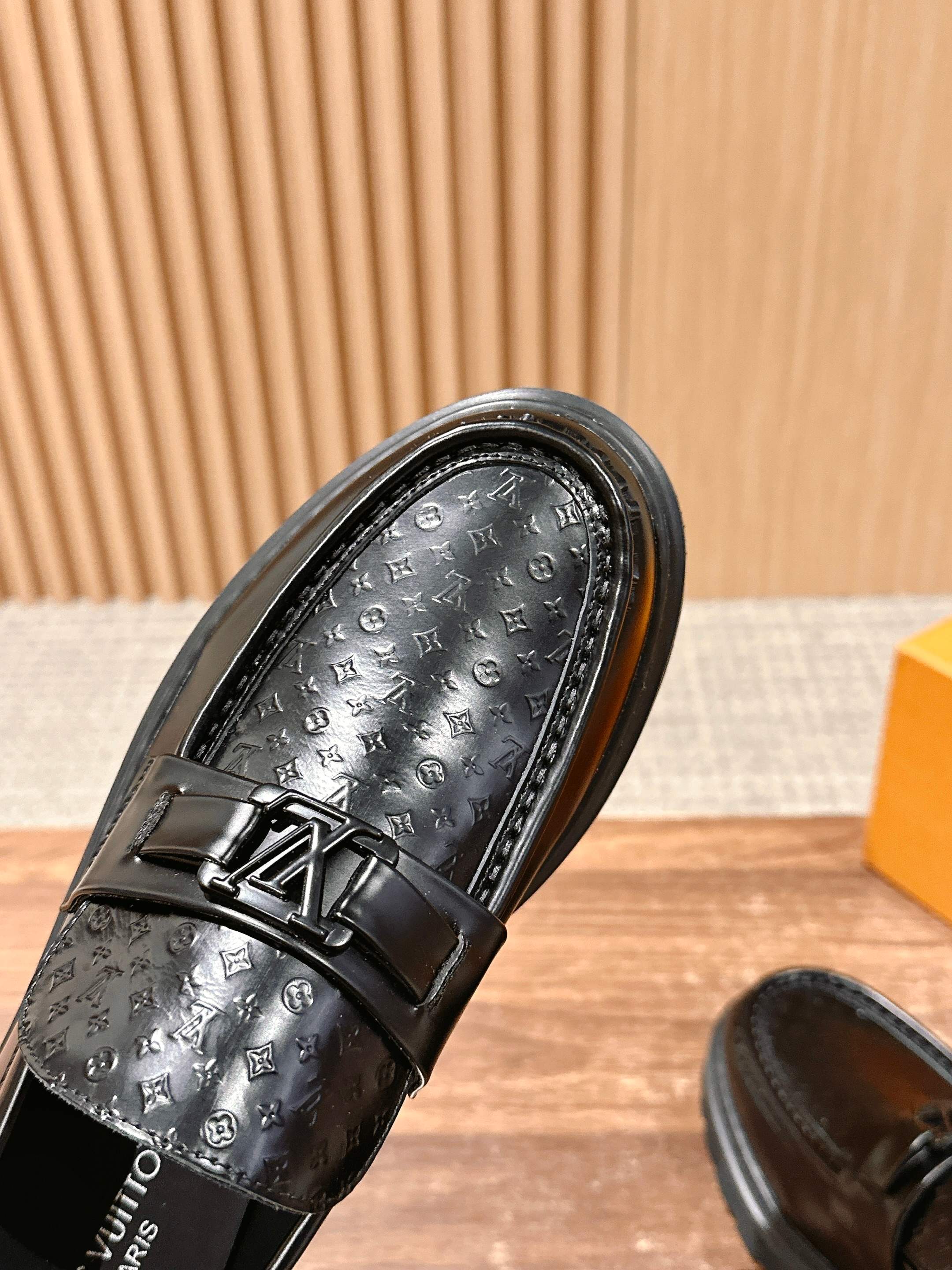 Close-up of black embossed monogram loafer with buckle strap over vamp