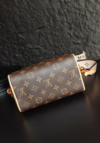 Brown monogram canvas handbag with cream trim, short strap, and small side charm