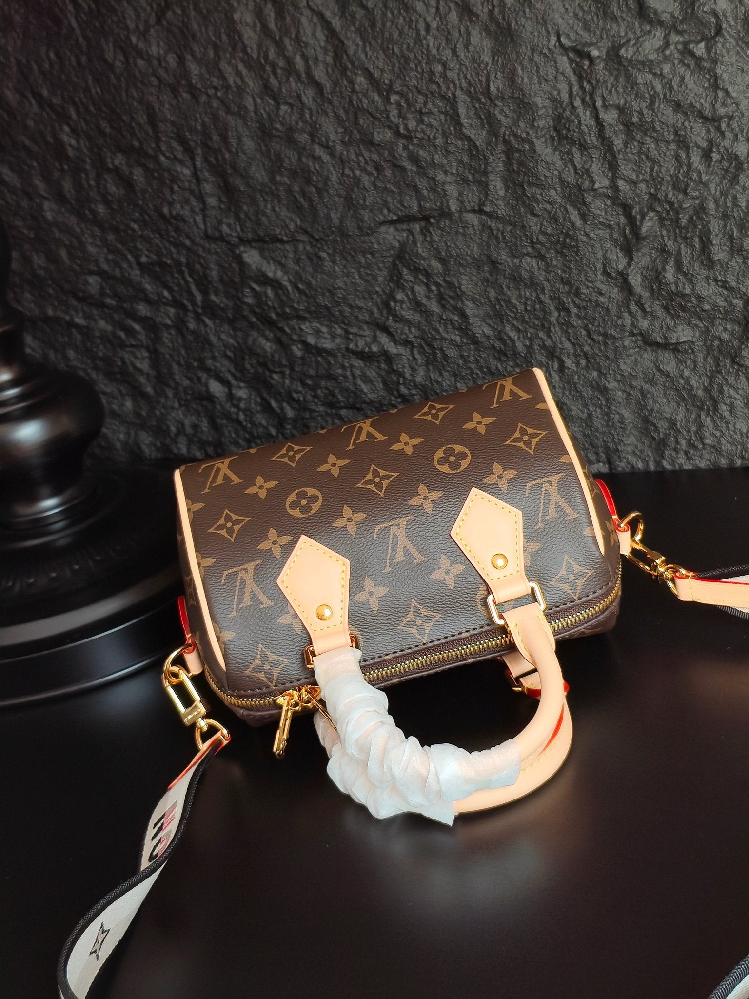 Brown monogram canvas handbag with gold-tone hardware, front zipper, and ruffled handle cover