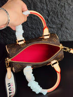 Brown monogram mini handbag with red interior view, cream trim, ruffled handle cover, zipper