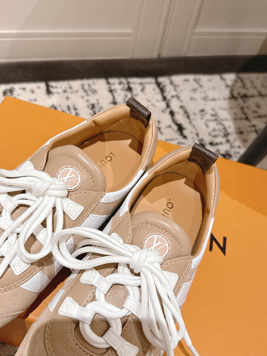 Pair of beige suede sneakers with white laces and tan interior lining