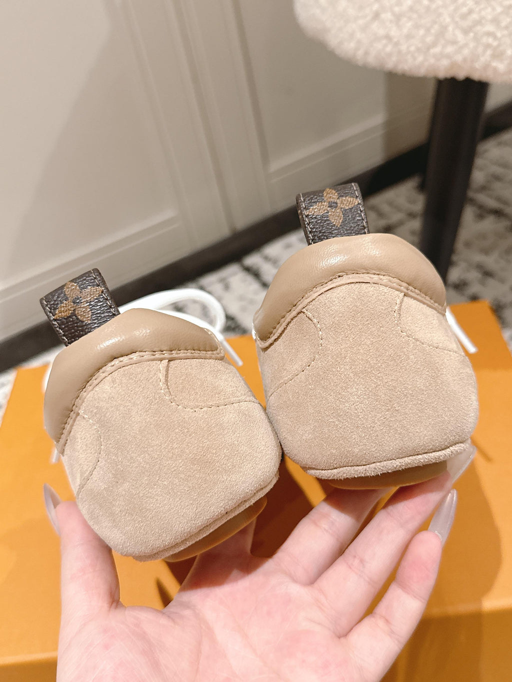 Beige suede sneakers with white laces and brown monogram heel tabs at back