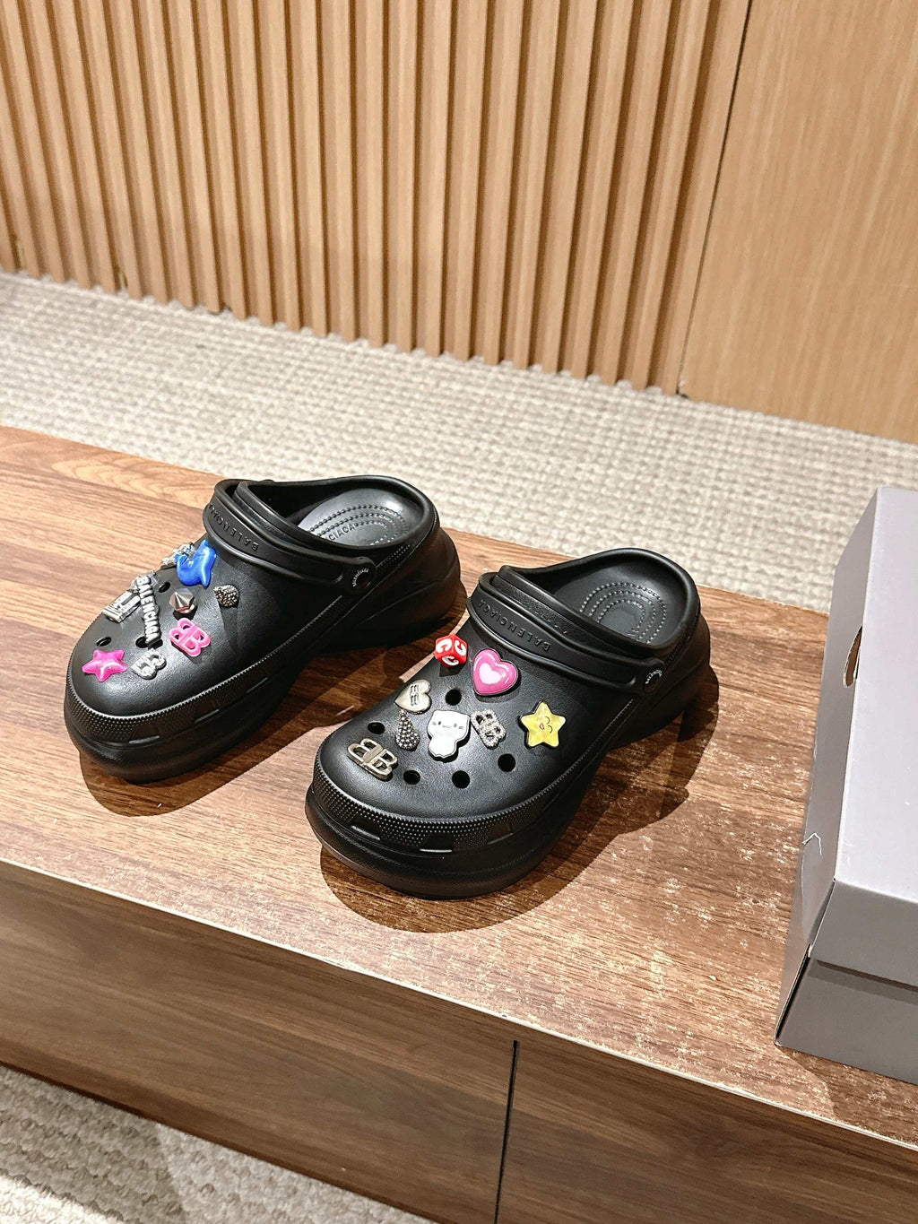 Balenciaga black clog sandals with colorful charms and perforated upper, side-by-side