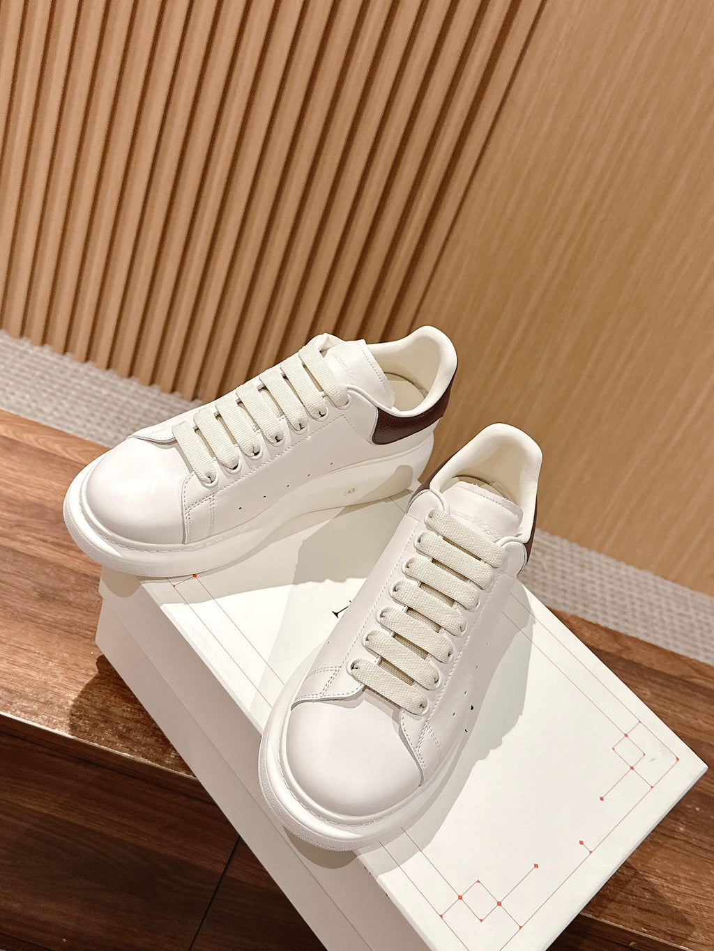 White leather low-top sneakers with lace-up closure and brown-trim heel collar