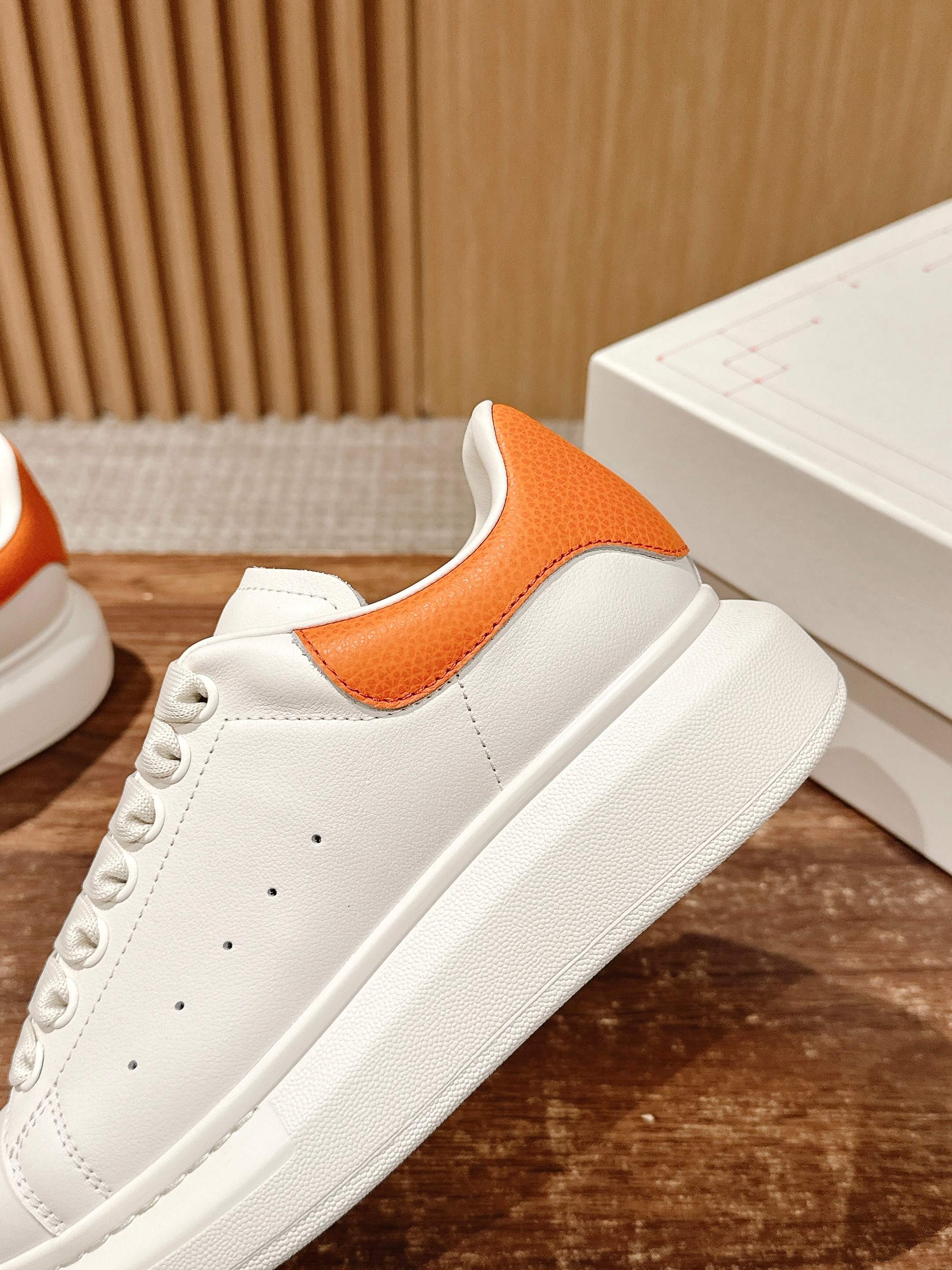 White leather sneaker with orange heel tab and perforated toe detail